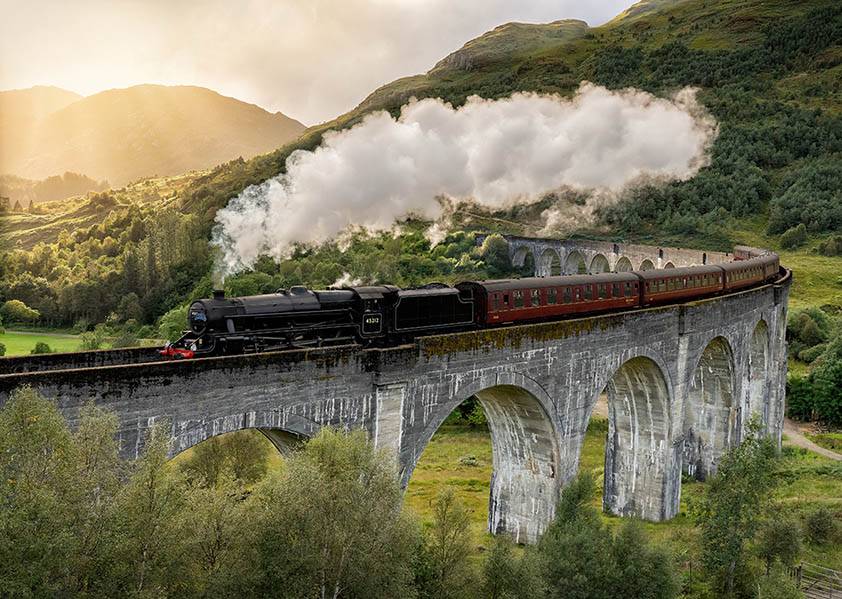 The Jacobite steam train puffing along the Glenfinnan Viaduct on a early summers day.