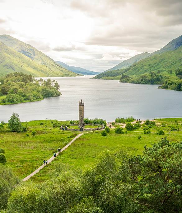 The Glenfinnan Monument stands tall on the shores of Loch Shiel amidst dramatic Highland scenery.