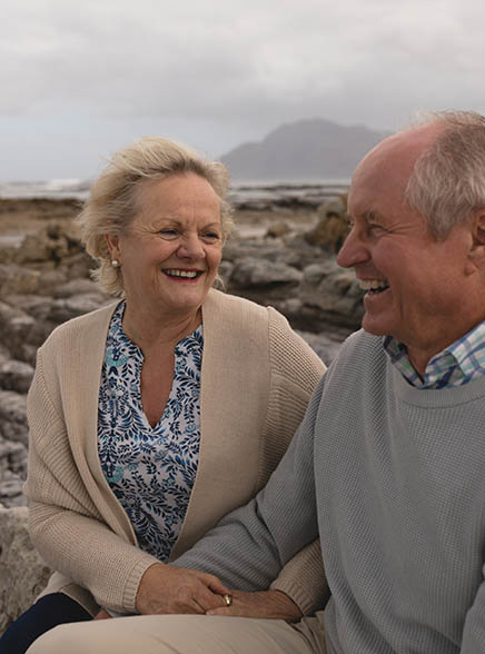 A couple sitting on a rocky beach in Scotland.